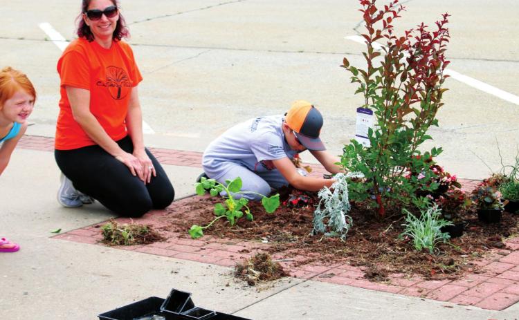 Bailey, Shawna and Caleb Swindell work to beautify their part of Broadway Saturday, during Cushing Pride’s May on Broadway event.
