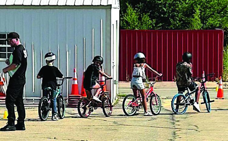 Participants of the Brandon Hise Memorial Bike Rodeo make their way through an obstacle course as Cushing Police Department members monitor and instruct in safe practices.