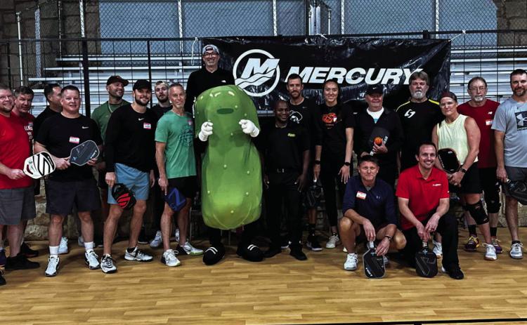 Tournament participants pose with Big Dill the mascot for Pickleman’s Gourmet Cafe, in Stillwater after the Mercury Marine Fourth Annual Pickleball Tournament.