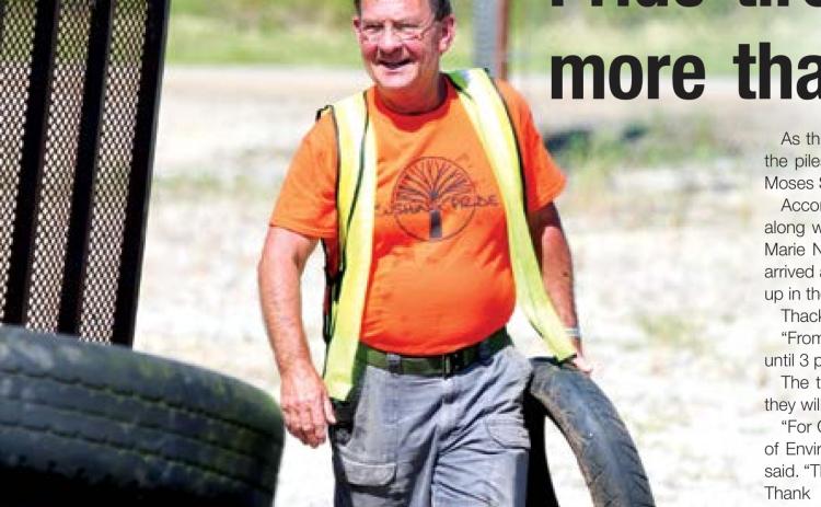 John Moran unloads a motorcycle tire from a trailer during Cushing Pride’s tire recycling event Saturday.