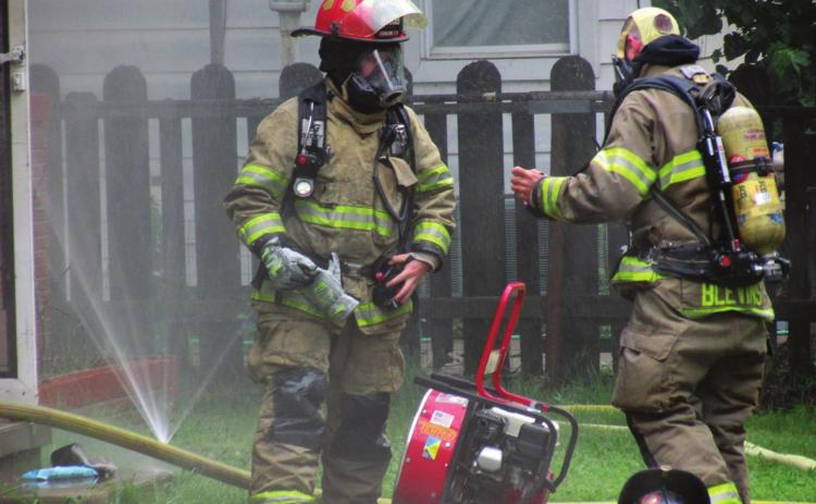 Firefighters Dakota Shadowen and James Blevins takes a moment to catch their breath before continuing to work against the fire at 1002 West Broadway on Tuesday, May 24. Photo by DeAnna Maddox