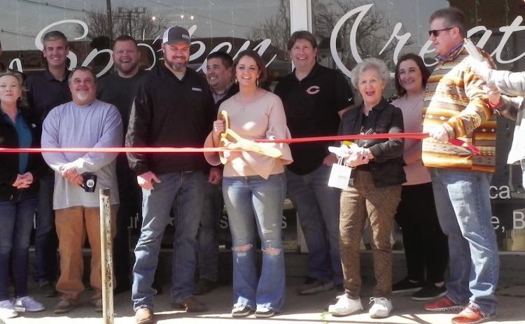 Members of the Cushing Chamber of Commerce stand with the owners of Spoken Creation, Kyle and Rachel Williams, during the ribbon cutting ceremony in front of their new business on Cleveland. Photo by Cayla DeHaas.