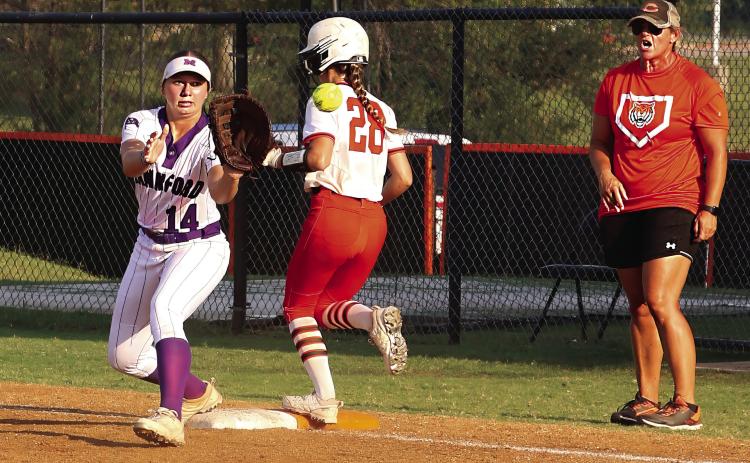 Cushing Lady Tiger junior Romy Withiam makes it to first base seconds before Mannford Lady Pirate first baseman Sydney Webster catches the ball as Lady Tiger head coach Nikki York watches from the coach’s box during the Lady Tigers game Tuesday, Aug 22. Photo by Allie Prater