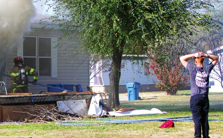 The grandson of the owner of this home on Greenlee watches distraught, as members of the Cushing Fire Department work to extinguish the fi re inside the building.