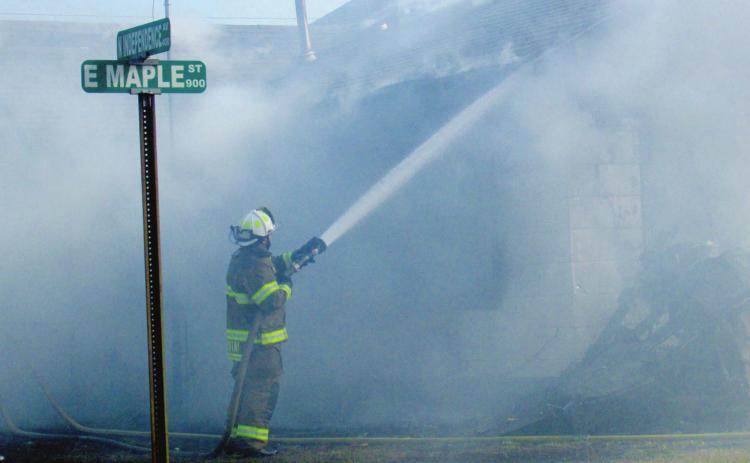 Deputy Fire Chief Dalton Novotny keeps a steady stream of water running over the home on the corner of Maple and Independence as the fire comes under control. The Cushing Fire Department stayed on scene for two hours to watch for hot spots and possible flares.
