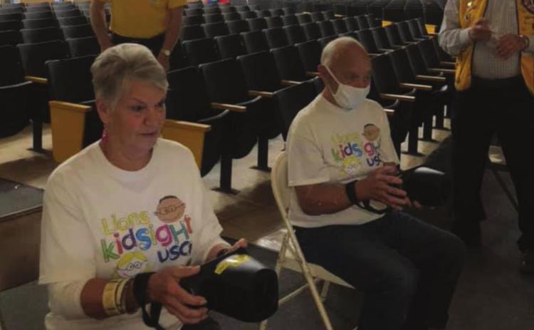 Cushing Lions Club members Lou Griffi n and Jim Pickard hold steady as they handle the cameras for Oak Grove School students being screened, while Tom Cummings and Russell Thurman supervise and hand out stickers in the background.