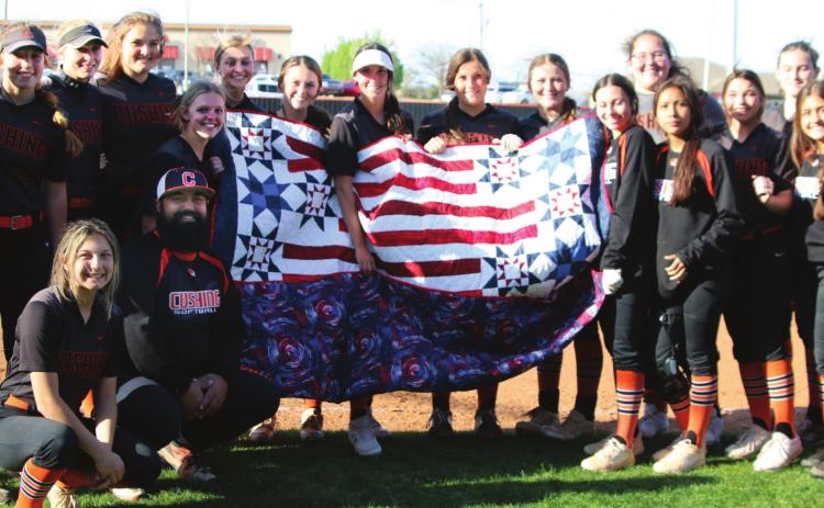 The entire Lady Tiger slowpitch softball team surrounds Assistant Coach Josh Encinas (kneeling) after he received his Quilt of Valor between games last Tuesday.