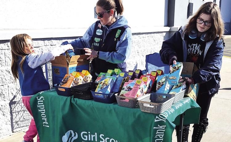 Local Girl Scout Troop 790 set up to sell cookies just outside Wal-Mart Sunday, Feb. 22, offering classic favorites to passersby during the annual cookie season fundraiser. Pictured from left: RayLynn Floyd, Troop Leader Rebecca Green, and Alice Green. Photo by DeAnna Maddox