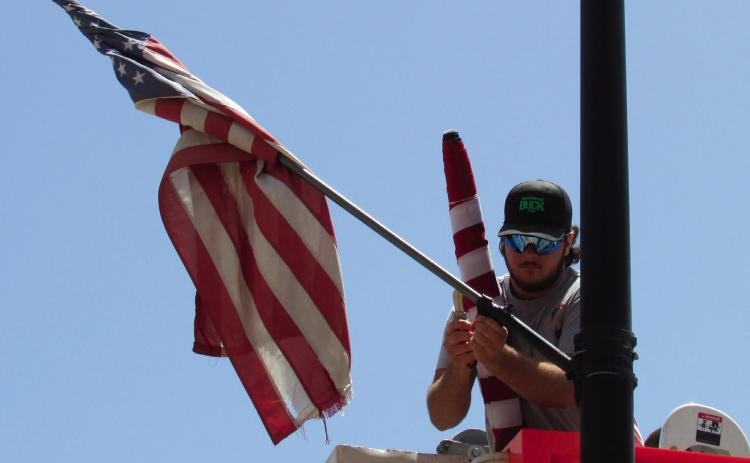 Apprentice lineman with the Electric Distribution department, Tagun Fittje, was replacing damaged flags in the Broadway District last week prior to the holiday festivities. As part of flag etiquette whenever a flag is worn or damaged beyond repair the flag should be destroyed by burning it.