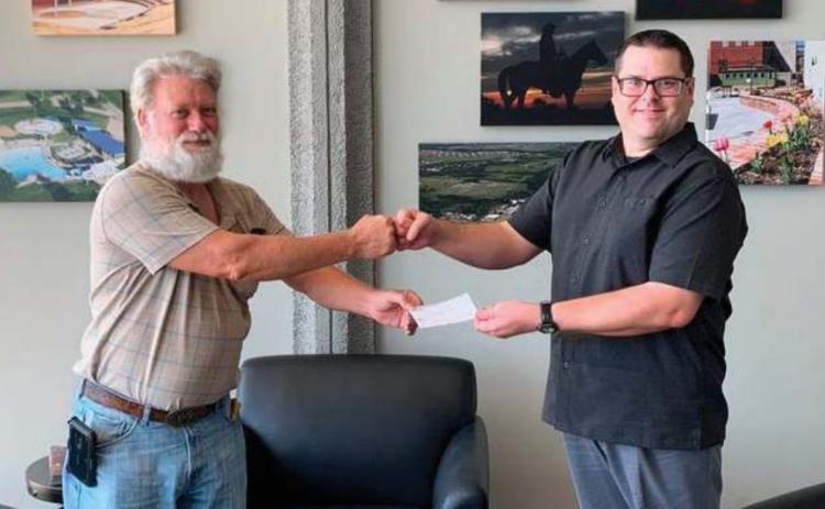 Charles Whittom, left, and Michael Hanes fi st bump as Whittom accepts a $900 donation from the Cushing Genealogical Society to support repairs to the Library’s microfi che machine.
