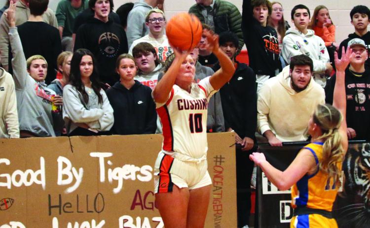 Katy Jones puts up a three pointer from the corner as members of “The Jungle” Cushing’s notorious student section, put their own energy into the shot.