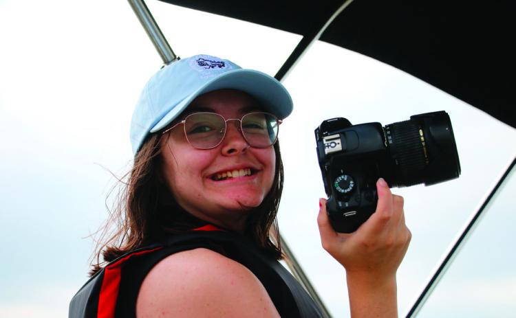 Raynee Howell smiling, camera in hand, while doing an ‘on the job’ interview with an USACE ranger on the lake patrol boat at Keystone Lake in May. Photo by Allie Prater